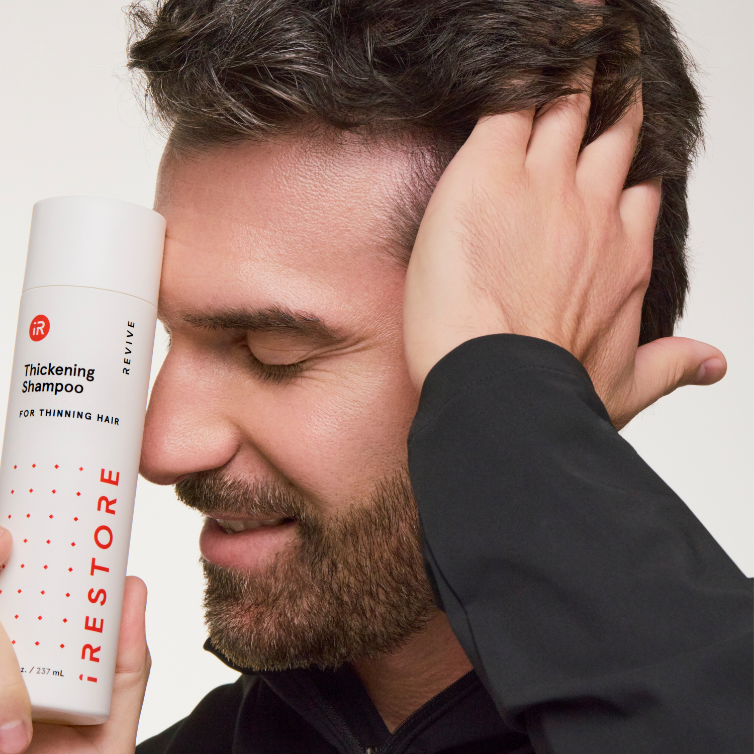 man holding a shampoo bottle near his face