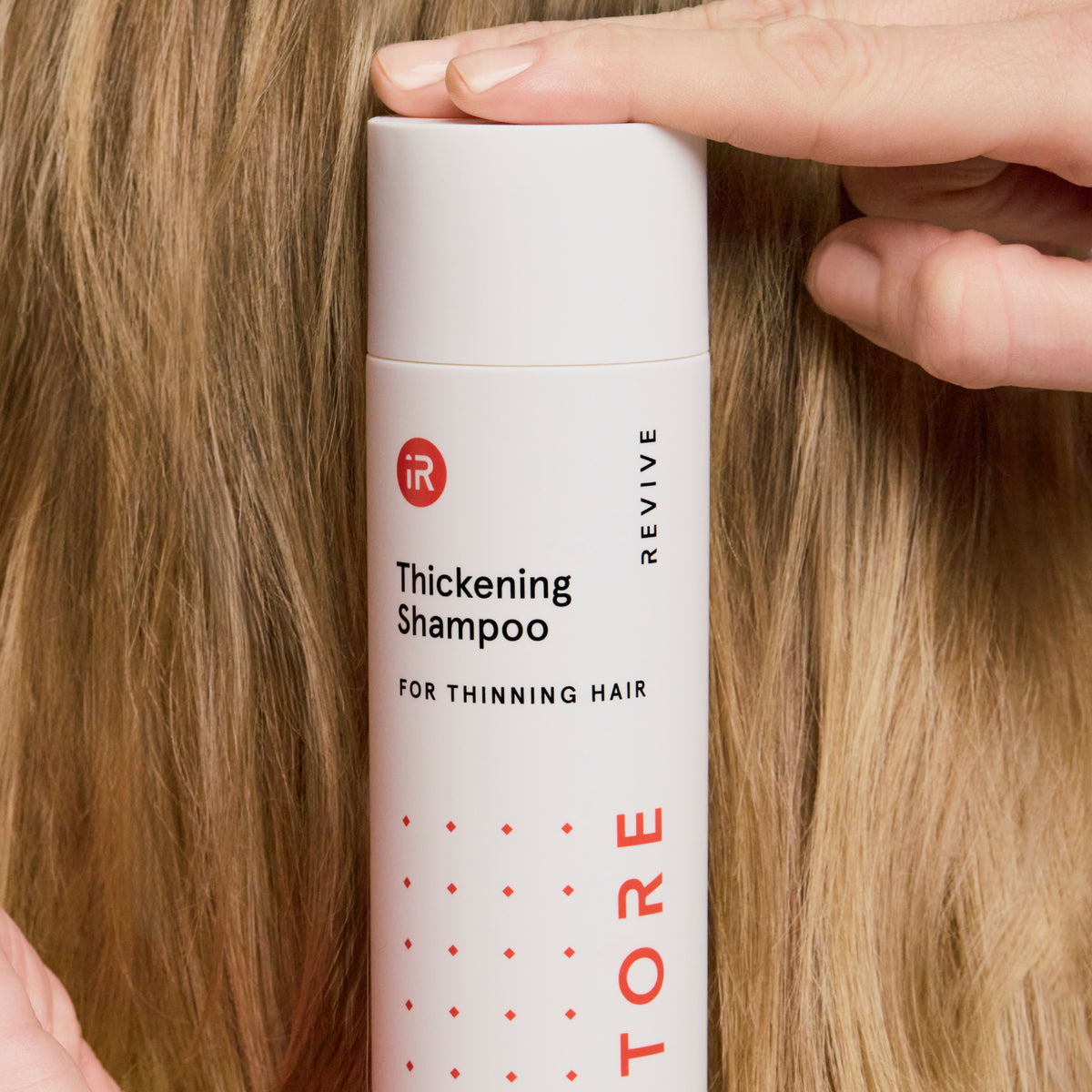woman holding a shampoo bottle behind her head