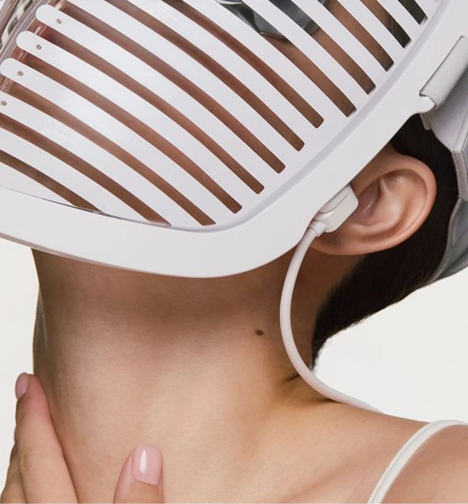  person wearing the face mask pro, showing the magnetic charging cable plugged into the side near the ear.
