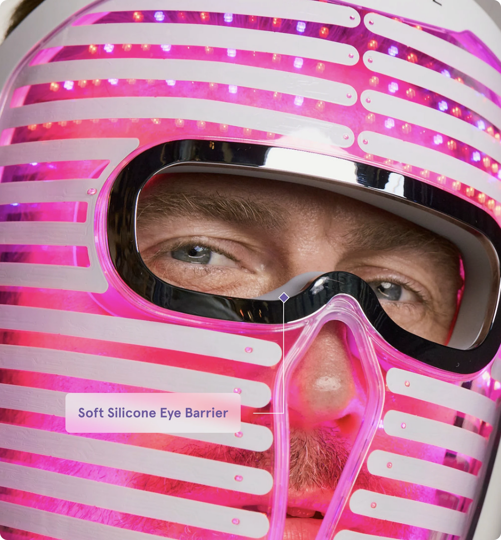 man wearing the Face Mask Pro glowing with bright magenta and purple LED light.