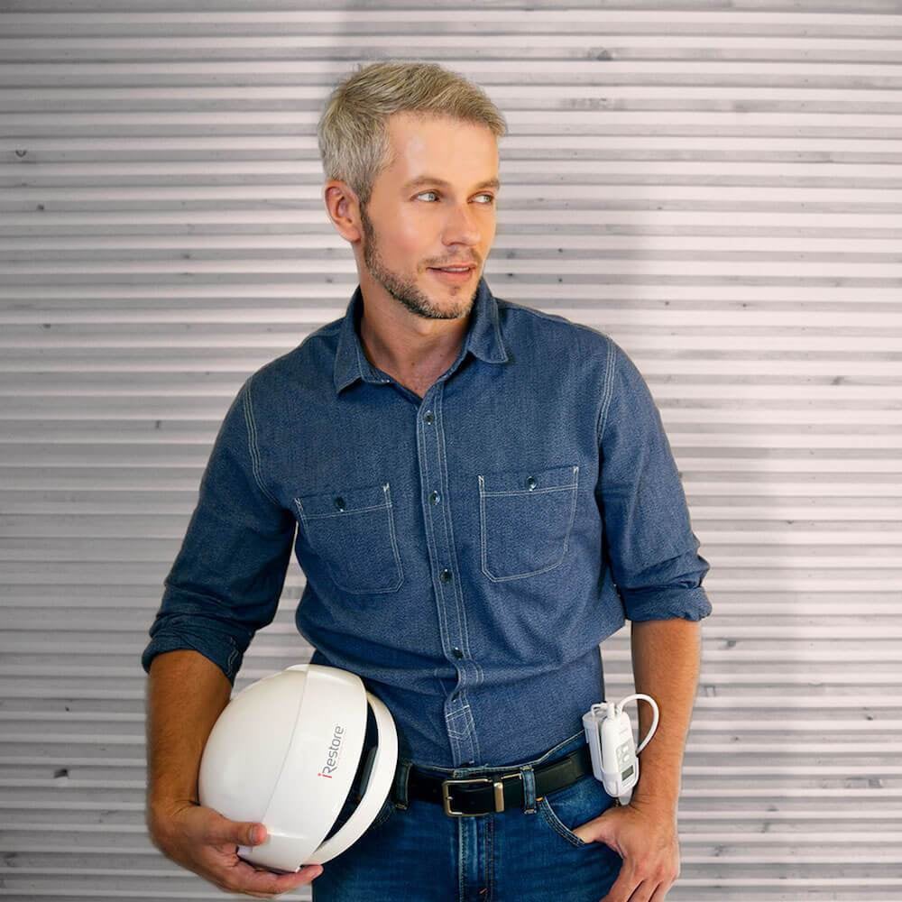 man holding the essential device while the battery pack is hanging on side of his pants