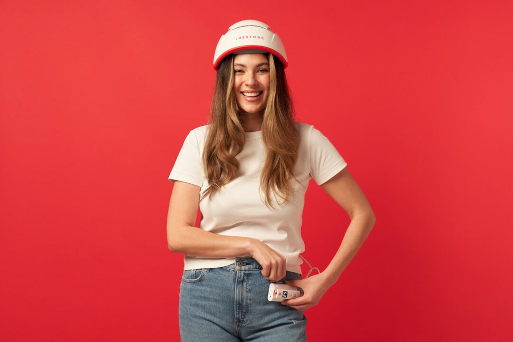 Woman wearing the  iRESTORE professional device while the device remote is in her pocket.