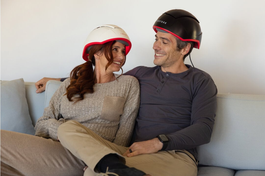 Image shows a woman wearing the Professional device and a man wearing the Elite device sitting on a couch.