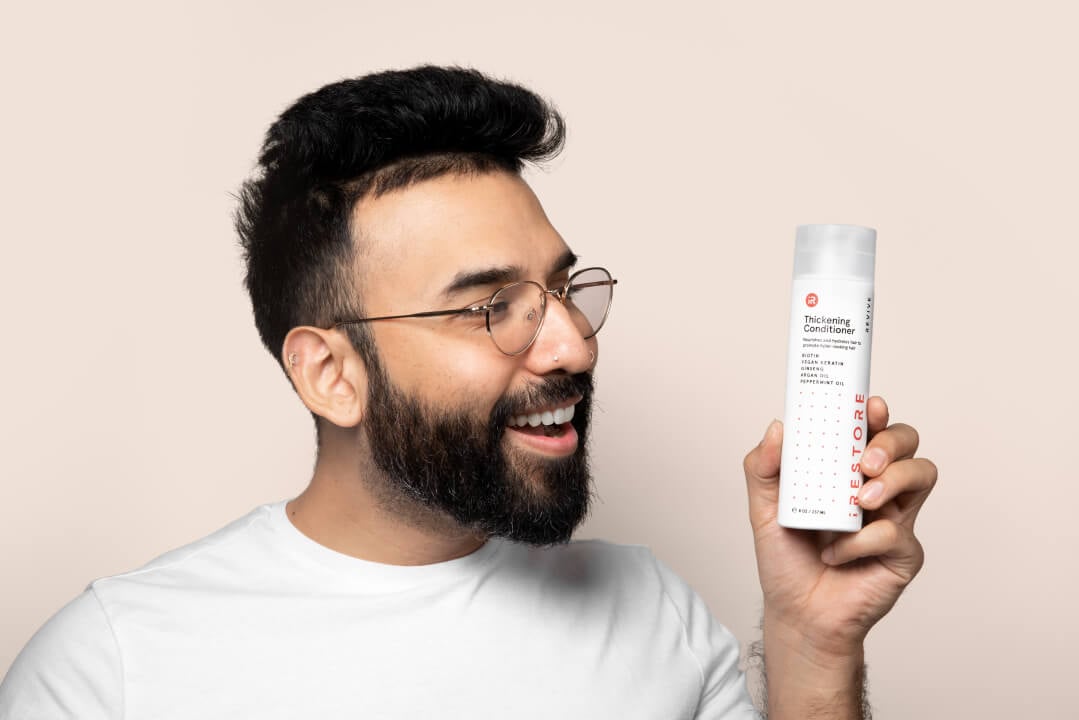 Image of a man holding the Thickening Shampoo.