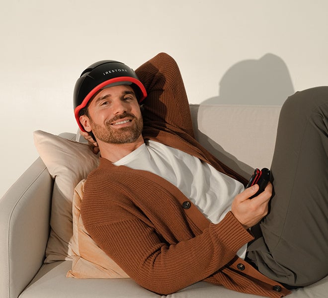 Image of a man wearing the Elite helmet device while laying on a couch.