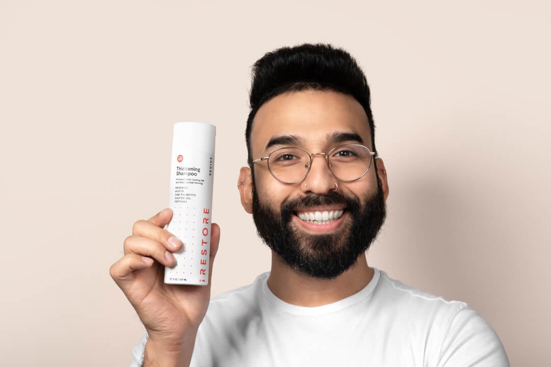 Image of a man holding the Thickening Shampoo bottle.