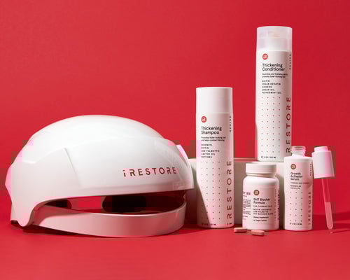 iRestore hair growth system including helmet, shampoo, conditioner, and supplements against a red background.