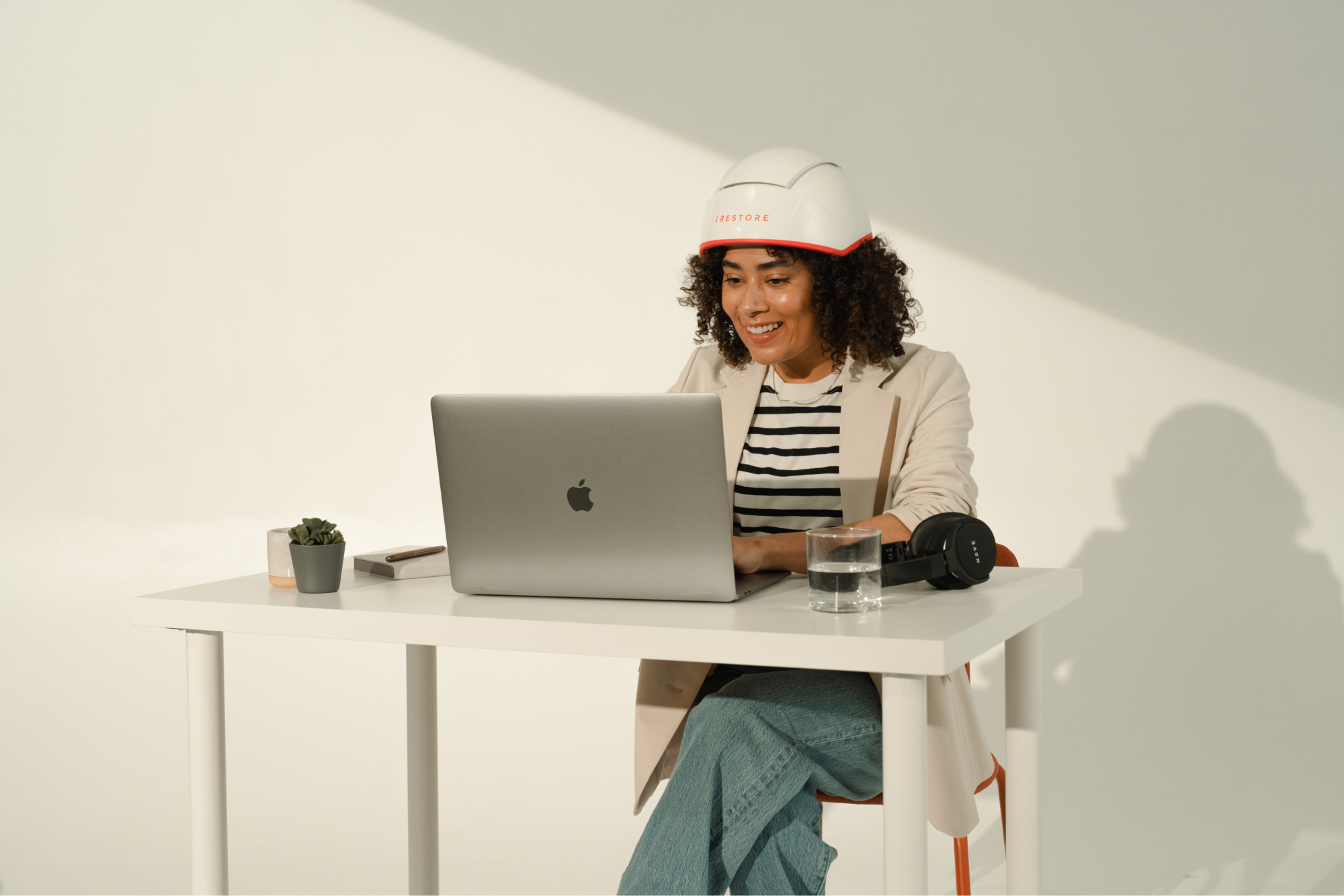 Person sitting at a desk, wearing a helmet, and using a laptop.