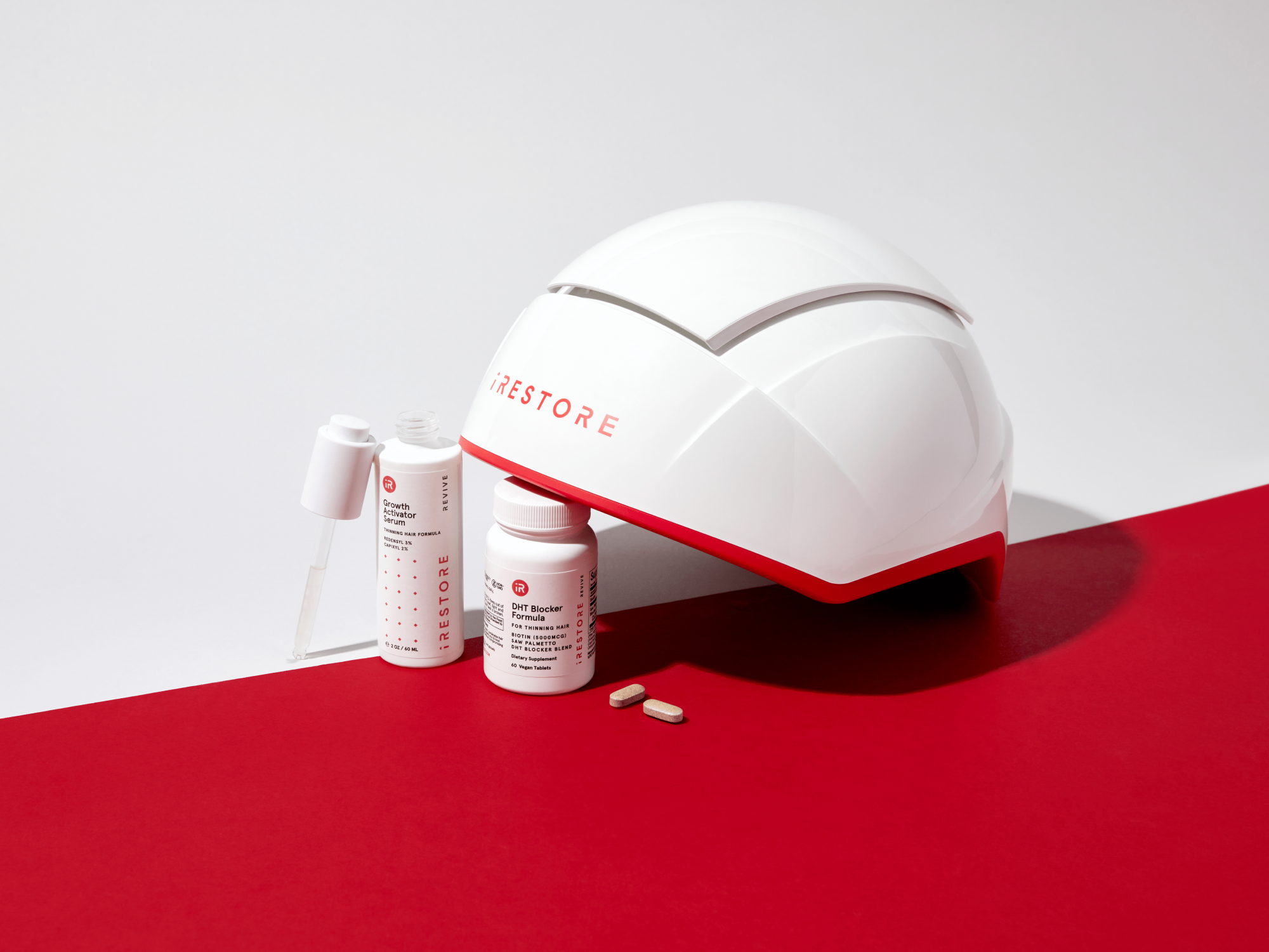 White iRestore hair growth helmet with hair growth serum and DHT blocker formula on red and white background.