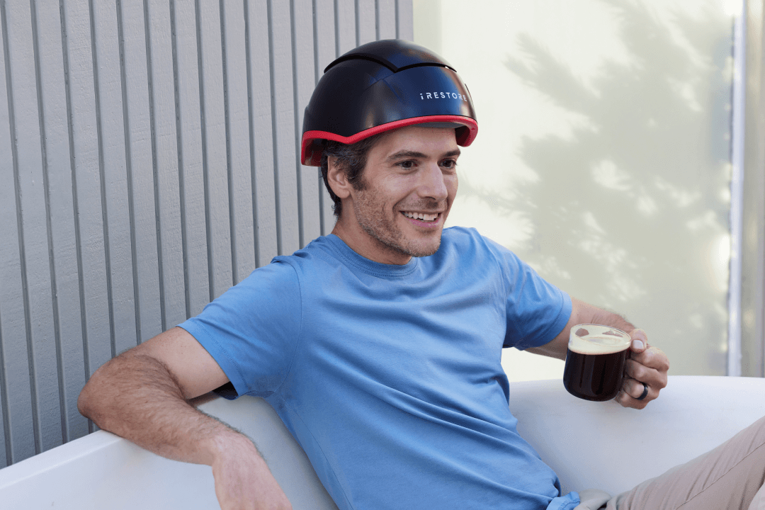 Man wearing the elite device while sitting and holding a cup of coffee.