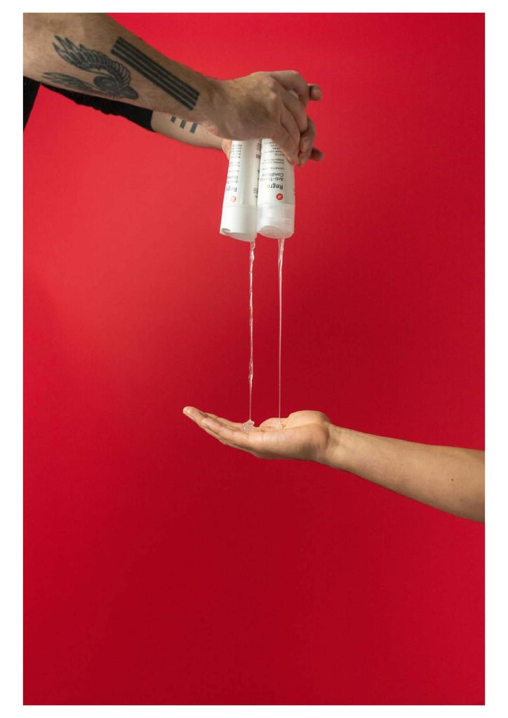 Image shows a close up shot of two persons hand. One person is holding the Thickening Shampoo and Conditioner bottles while dispensing its content to the other persons hand.