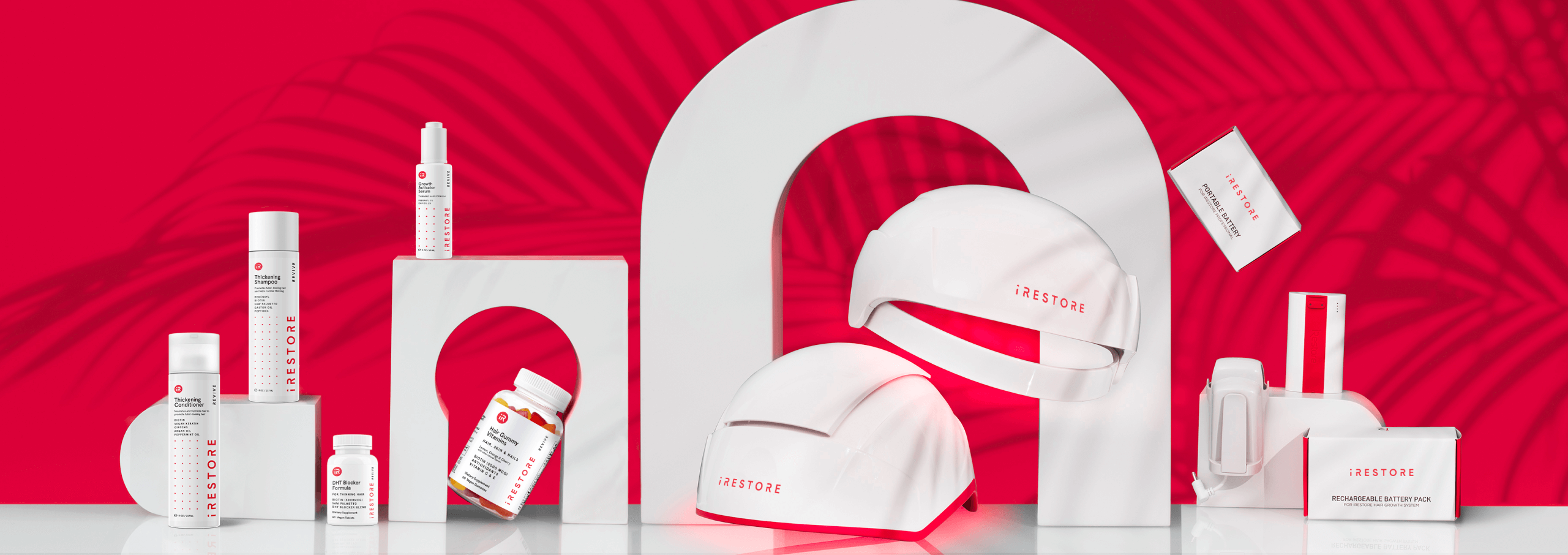 Image banner showing the products from iRESTORE. Including Professional Device, Essential Device, Biotin Vitamin Gummies, Thickening Shampoo and Conditioner, Growth Activator Serum and battery packs.