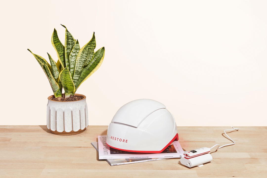 Image showing the Professional device with battery pack. Placed on top of a magazine in a wood-like table with plant as the background.
