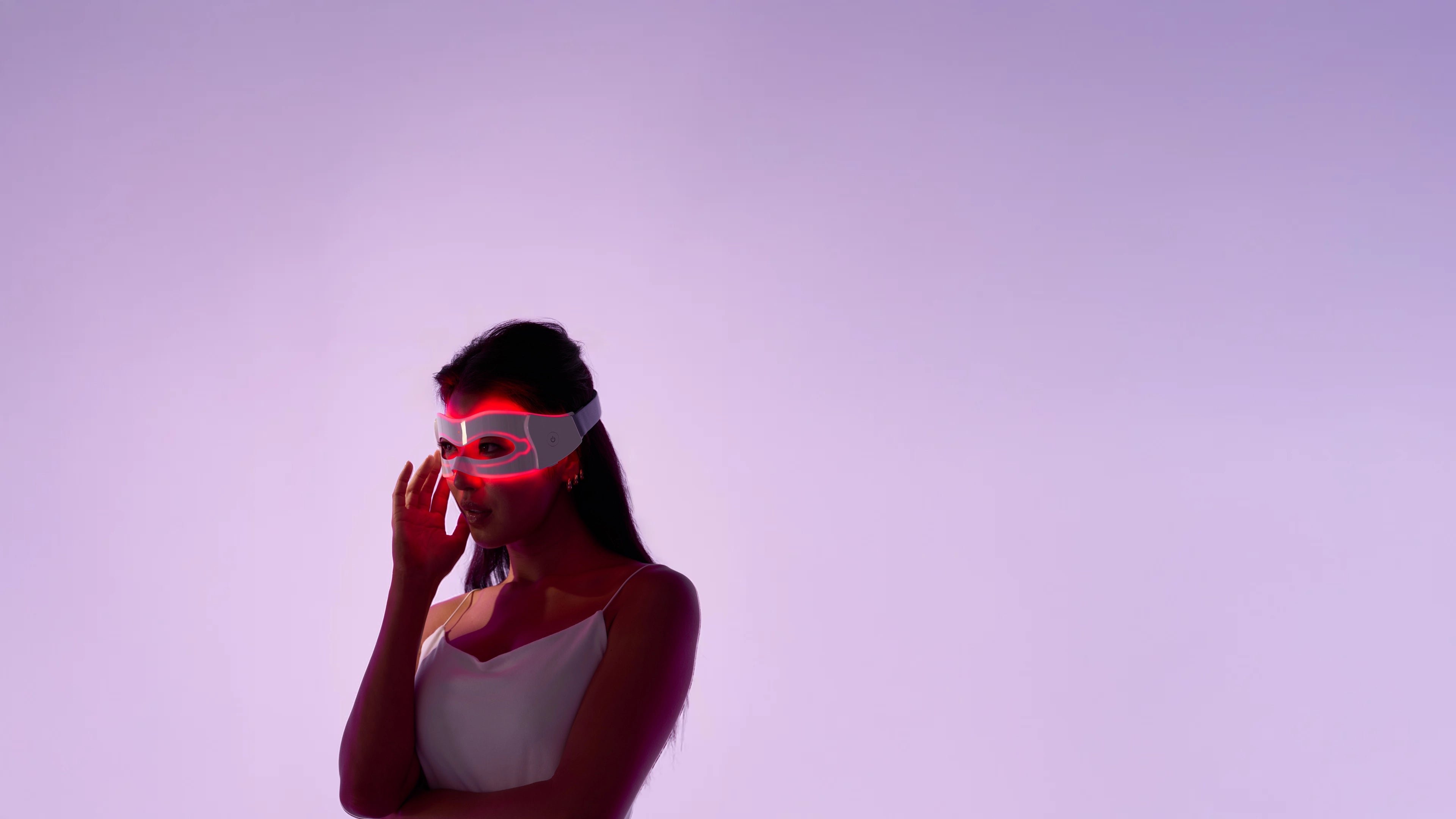 Person wearing a futuristic mask with red lights on a purple background.