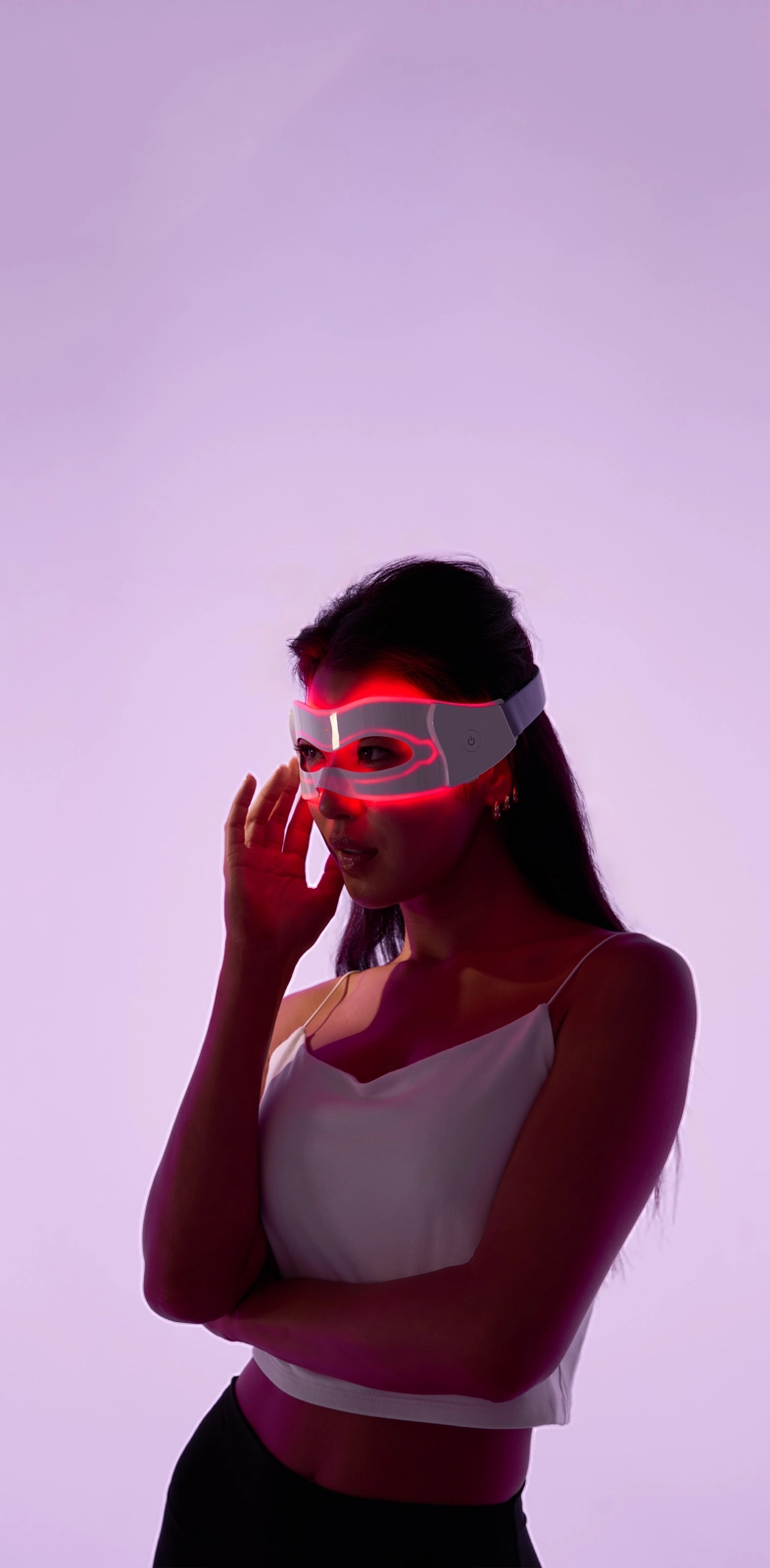 Person wearing a futuristic LED mask with a pink glow on a purple background.