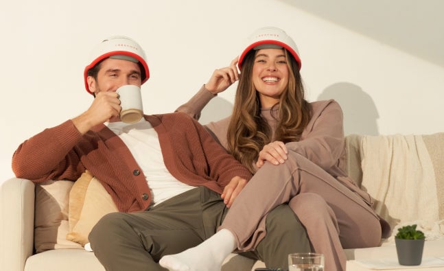 Image of a man and woman wearing the Professional Device sitting on a couch.